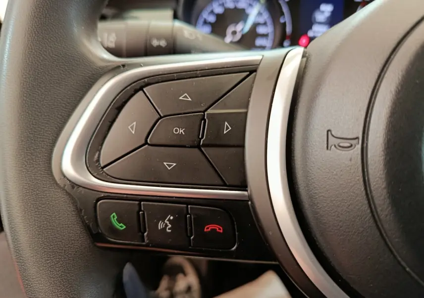 Gros plan sur les commandes multifonctions du volant noir du Fiat 500X 2020, avec boutons appel et navigation.