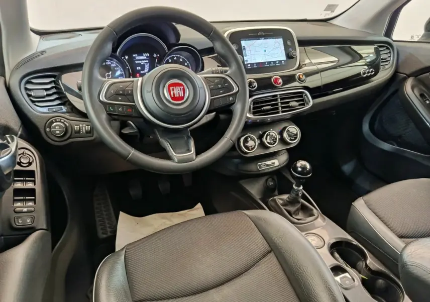 Vue intérieure avant de la Fiat 500X 2020 avec tableau de bord noir, volant multifonctions et écran tactile central.