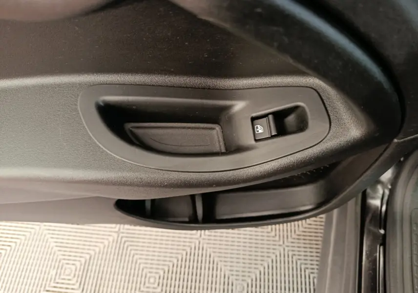 Gros plan sur la poignée intérieure noire et le bouton de verrouillage de la porte côté conducteur d'une FIAT 500X blanche.