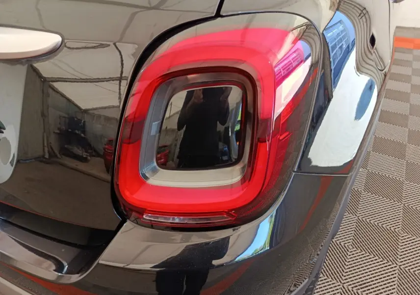 Gros plan sur le feu arrière droit rouge et noir d’un FIAT 500X noir, avec reflet de l’environnement.