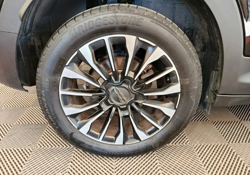Gros plan sur la roue avant droite d'une FIAT 500X blanche, avec jante alliage et pneu Bridgestone.