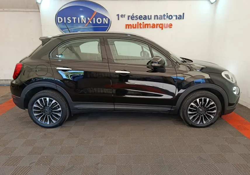 Vue latérale droite d'un FIAT 500X noir 2020 avec jantes alliage et rails de toit noirs en intérieur showroom.
