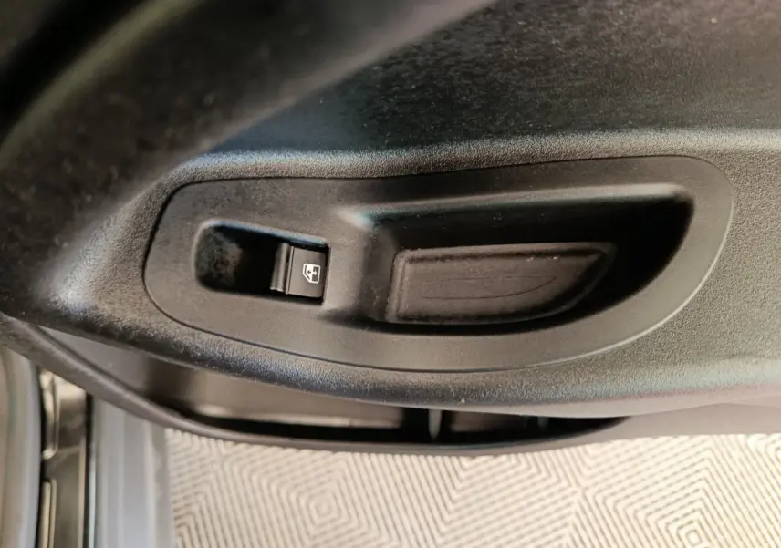 Gros plan sur le bouton de commande de la vitre électrique côté conducteur d'une Fiat 500X blanche.