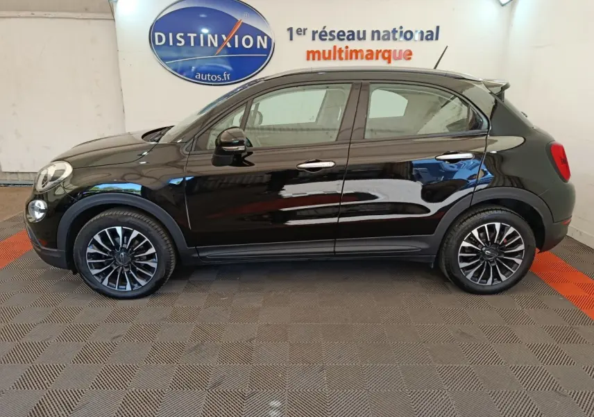 Profil côté gauche d'un FIAT 500X noir avec jantes alliage et toit noir, en intérieur sur sol damier.