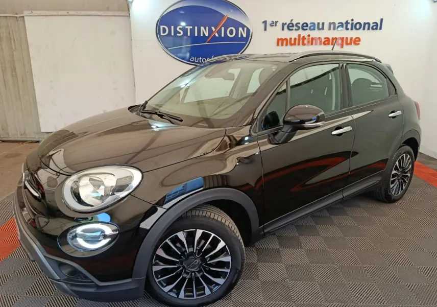 Vue 3/4 avant droit d'une FIAT 500X noire avec jantes alliage et toit ouvrant en intérieur showroom.
