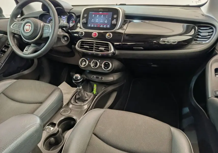 Vue intérieure avant droite du tableau de bord noir brillant et volant cuir de la Fiat 500X 2020 avec écran tactile central.