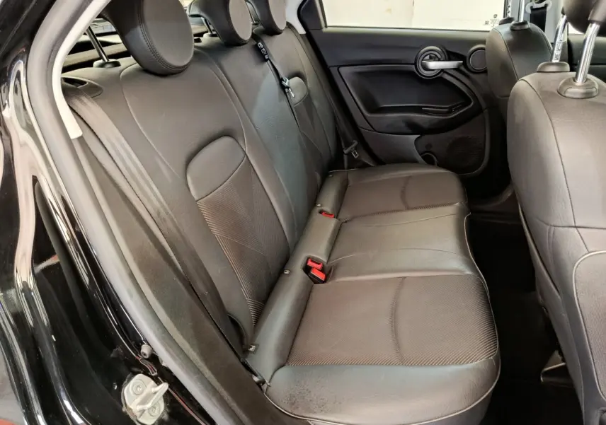 Banquette arrière en cuir noir vue côté gauche dans une FIAT 500X Cross blanche, porte ouverte.
