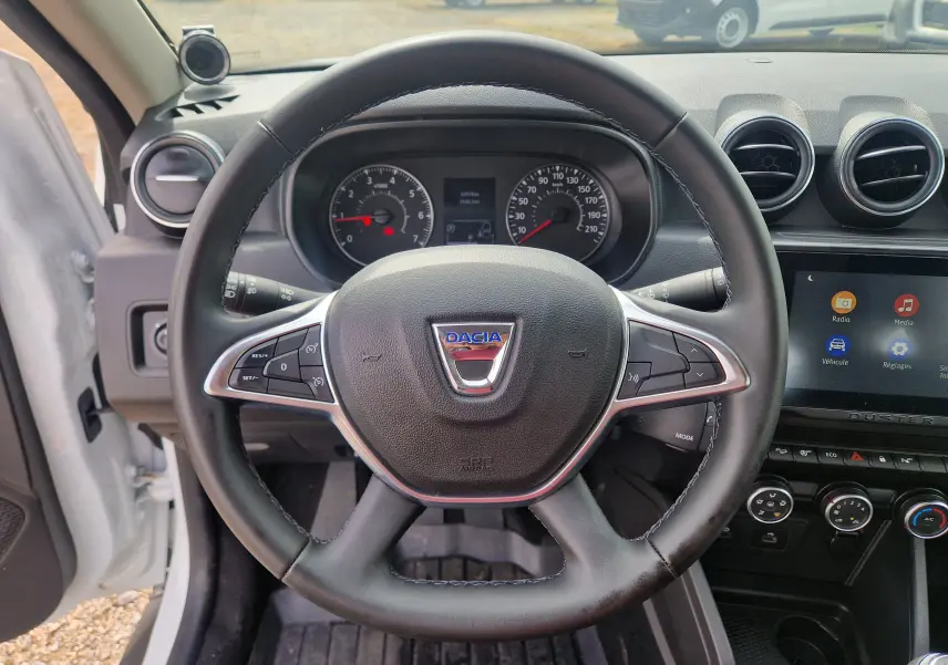 Vue intérieure centrée sur le volant noir du Dacia Duster 2022, avec tableau de bord et écran tactile visibles.