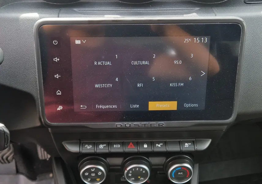 Écran tactile central du tableau de bord du Dacia Duster 2022 avec commandes climatisation et boutons fonctionnels.
