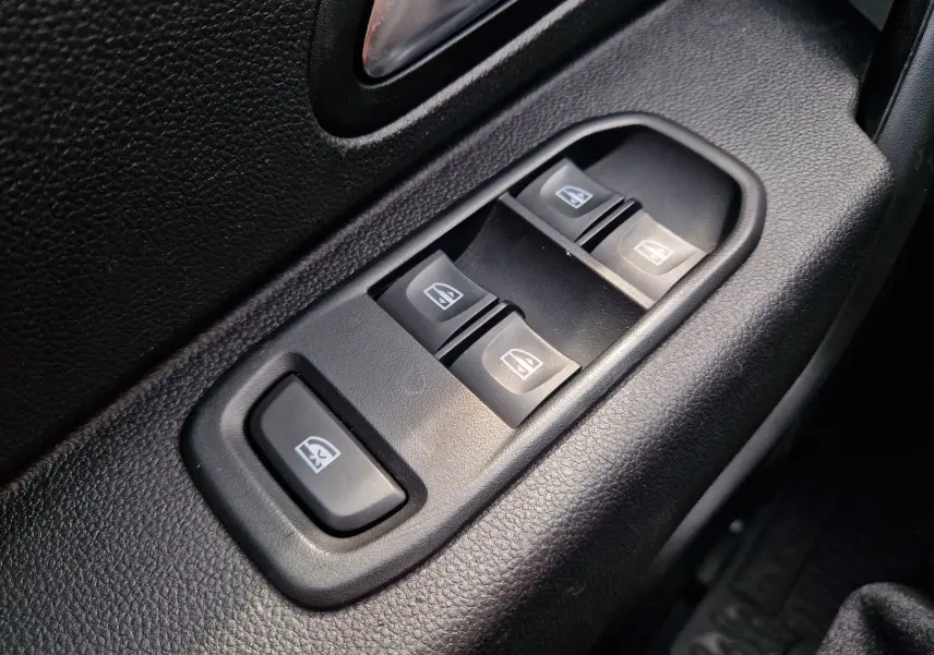Gros plan sur les commandes de lève-vitres électriques côté conducteur du Dacia Duster blanc 4x4 2022.