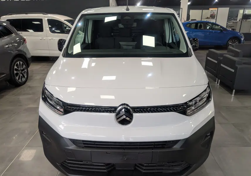 Vue frontale d’un Citroën Berlingo blanc 2025 avec calandre noire et pare-chocs avant noir mat en showroom.