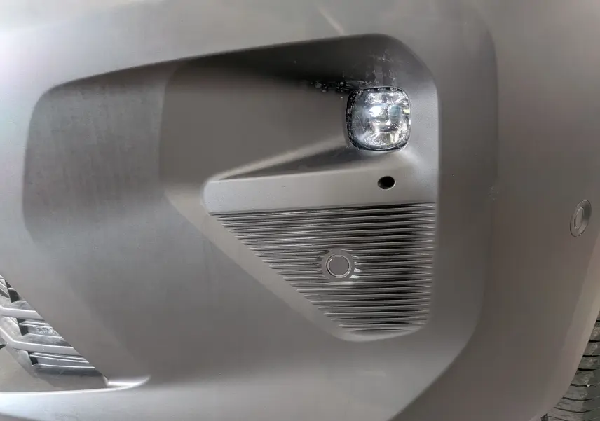 Gros plan sur le pare-chocs avant droit blanc du Citroën Berlingo 2025 avec antibrouillard et capteur de stationnement.