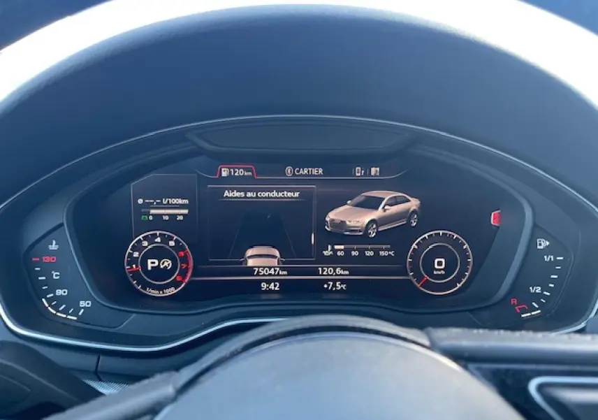 Tableau de bord numérique d'une Audi A4 argent, affichant aides au conducteur et compteurs à 9h42.