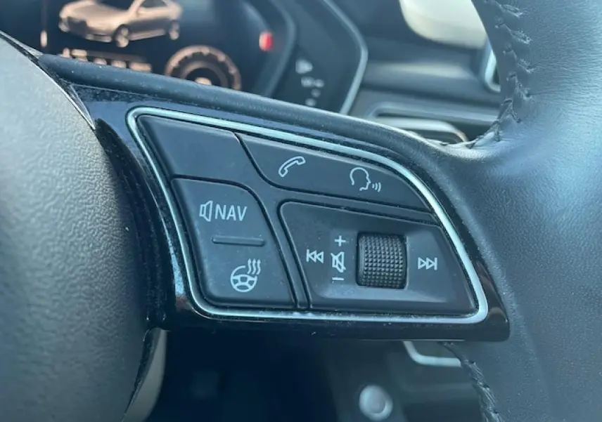 Gros plan sur les commandes audio et navigation du volant cuir noir de l'Audi A4 S line argent 2019.
