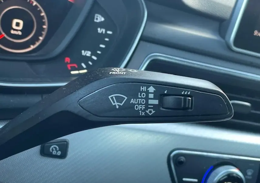 Gros plan sur la commande des essuie-glaces d'une Audi A4 argent, avec tableau de bord et console en arrière-plan.