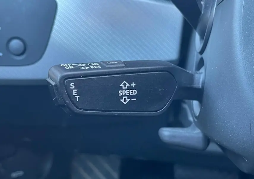 Gros plan sur la commande de régulateur de vitesse noire à gauche du volant d'une Audi A4 argent Fleuret Metal 2019.