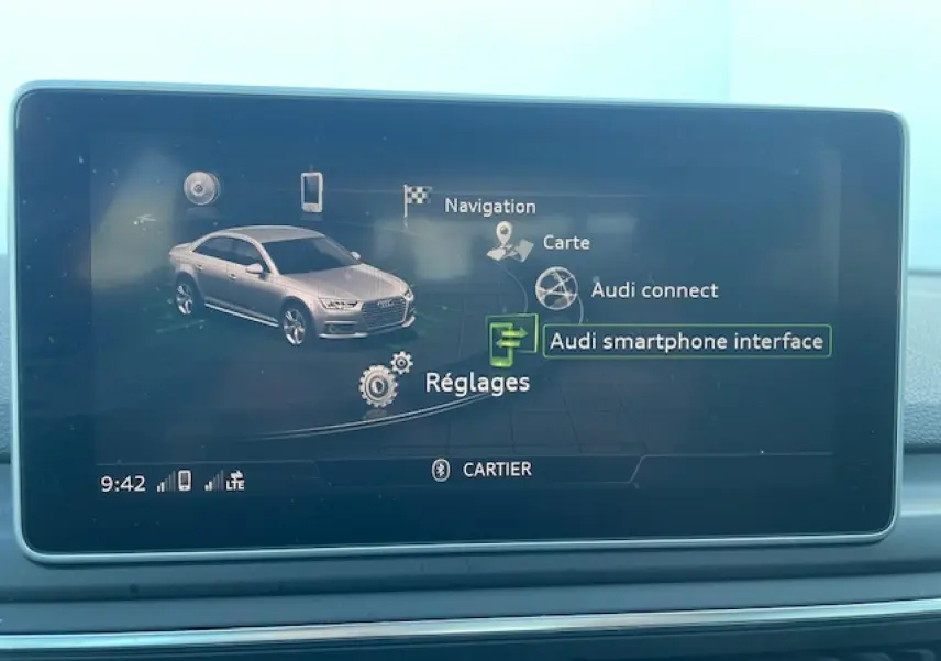 Écran central affichant l'interface multimédia de l'Audi A4 argent, avec menu navigation et réglages visibles.