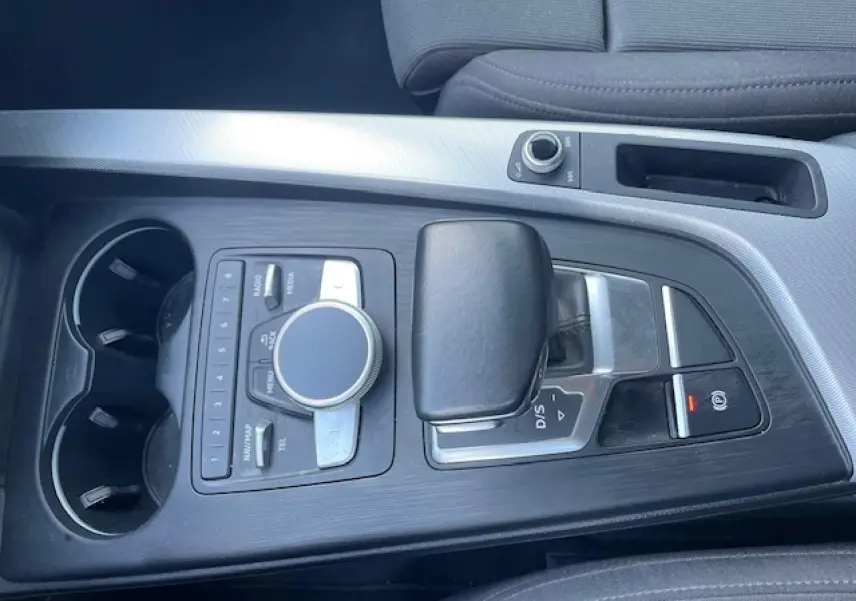 Vue plongeante sur la console centrale noire avec levier de vitesses automatique et commandes multimédia d'une Audi A4 argentée de 2019