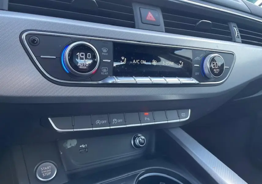 Tableau de bord argenté de l'Audi A4 2019 avec commandes climatisation 3 zones et boutons multifonctions au centre