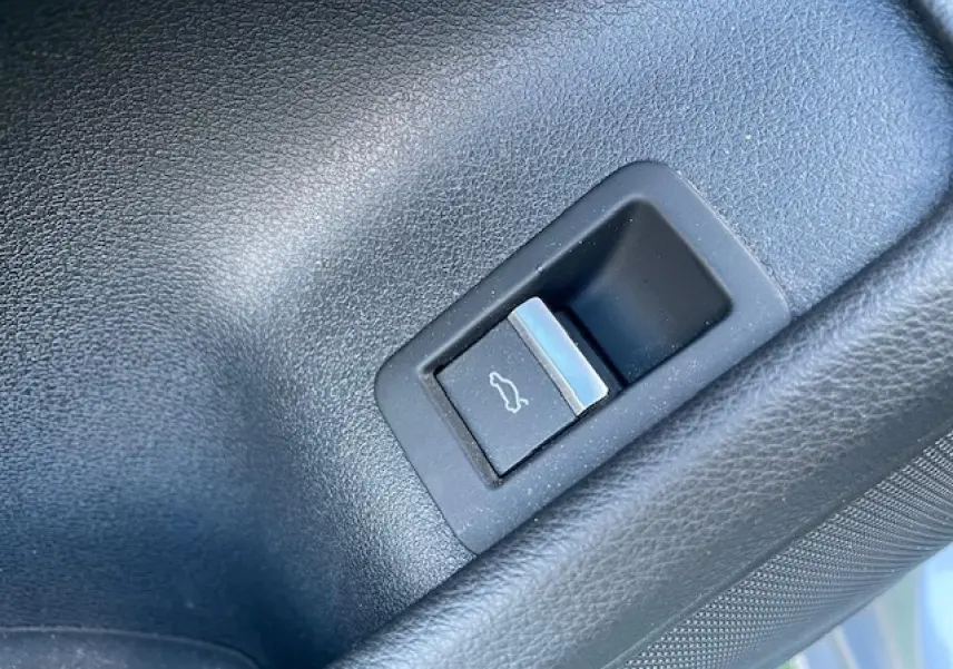 Bouton d'ouverture du coffre en plastique noir dans le coffre d'une Audi A4 argent Fleuret Metal de 2019.