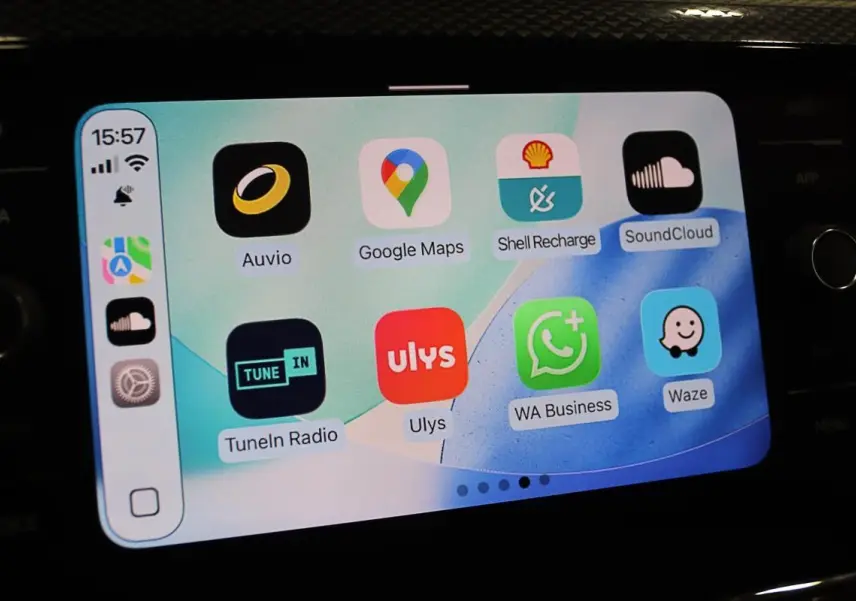 Écran tactile du système Apple CarPlay dans une Volkswagen Polo noire, affichant plusieurs applications de navigation et musique.