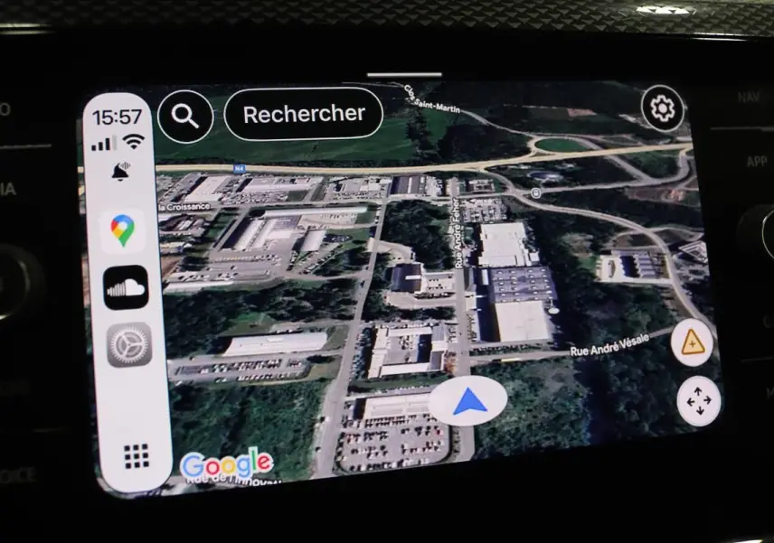 Écran tactile du système GPS Apple CarPlay dans une Volkswagen Polo noire, affichant une carte satellite détaillée.