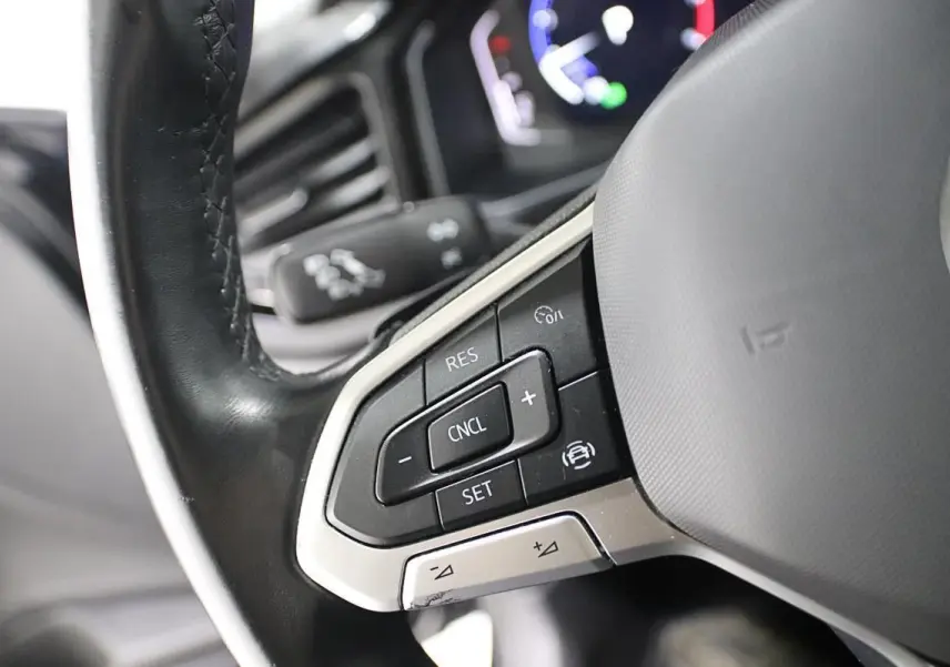 Gros plan sur les commandes au volant noir de la Volkswagen Polo 2022 avec régulateur de vitesse et finition argentée.