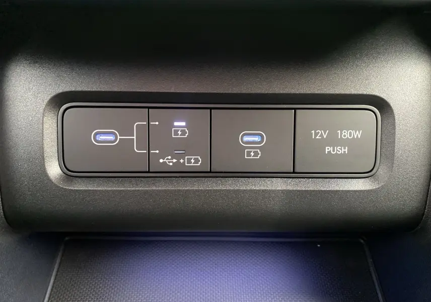 Gros plan sur les ports USB et prise 12V du Hyundai Tucson 2026 gris Shadow, avec éclairage bleu subtil.