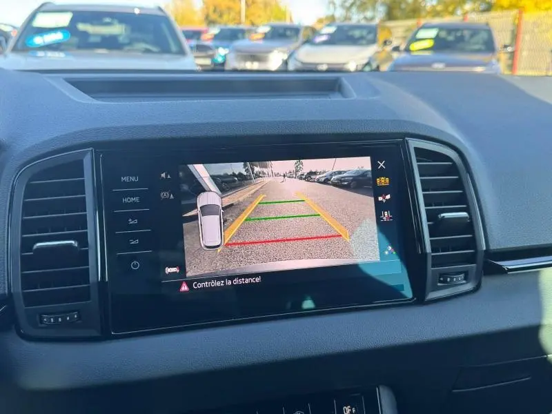 Écran tactile intérieur montrant la caméra de recul du Skoda Karoq gris, vue arrière avec lignes de guidage colorées.