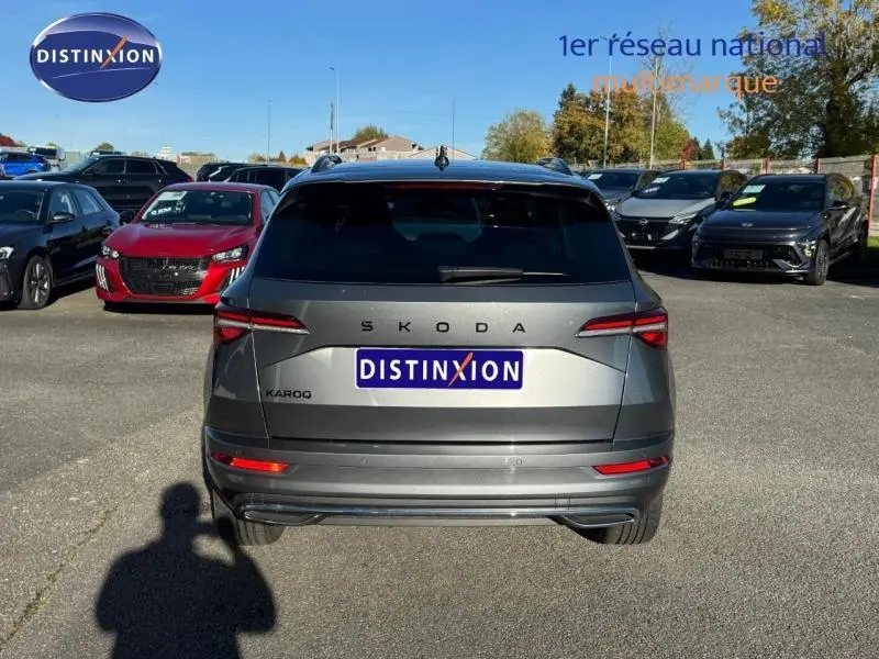 Vue arrière d'un Skoda Karoq gris perle 2025, avec feux LED et barres de toit visibles en extérieur.