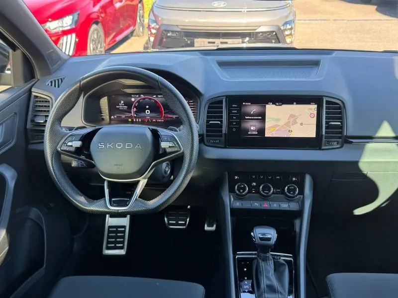 Vue intérieure frontale du tableau de bord gris d’un Skoda Karoq 2025 avec volant cuir multifonction et écran tactile GPS.