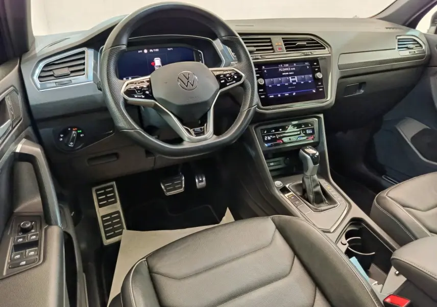 Intérieur noir du Volkswagen Tiguan 1.4 eHybrid 2023, vue côté conducteur sur volant multifonctions et écran tactile central.