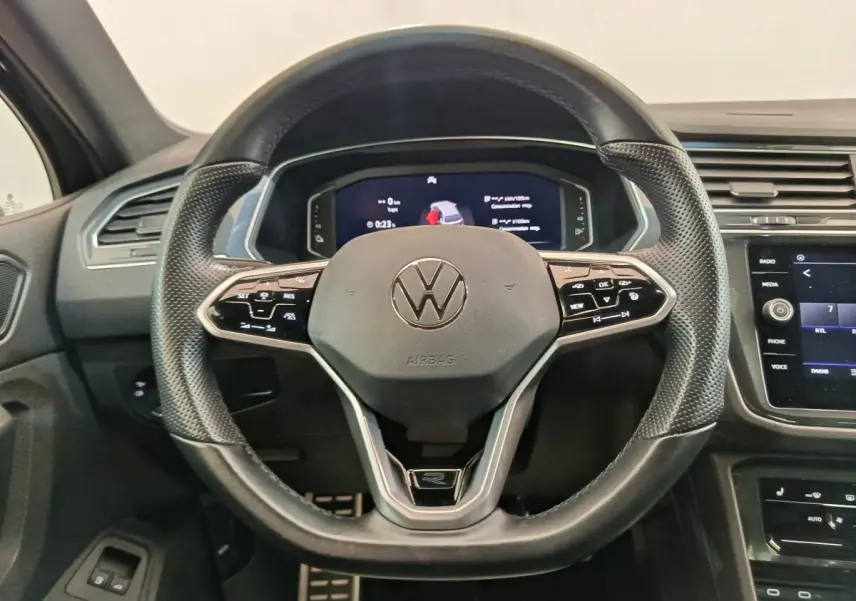 Vue intérieure centrée sur le volant cuir multifonctions du Volkswagen Tiguan noir avec tableau de bord digital.