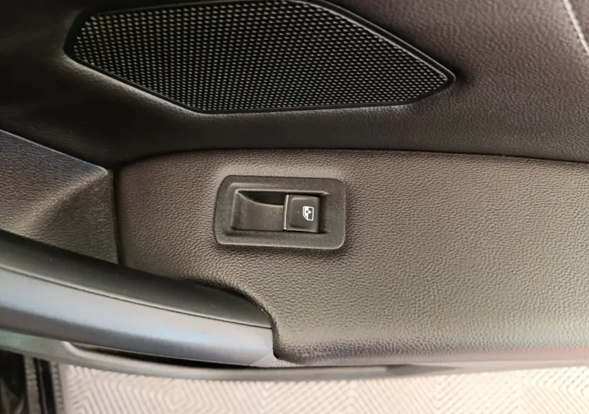 Détail de la commande de lève-vitre sur la porte intérieure noire du Volkswagen Tiguan 1.4 eHybrid 2023.