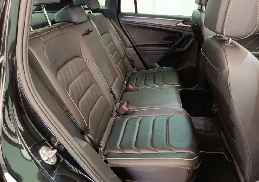 Vue intérieure côté gauche des sièges arrière en cuir noir du Volkswagen Tiguan 1.4 eHybrid 2023 avec portes ouvertes.