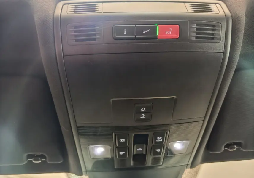 Vue du plafond intérieur du Volkswagen Tiguan 2023 noir, avec commandes d'éclairage et bouton SOS rouge allumé.