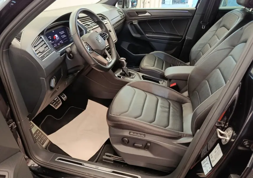 Intérieur avant droit du Volkswagen Tiguan noir 2023, sièges cuir et tableau de bord digital avec volant multifonctions.