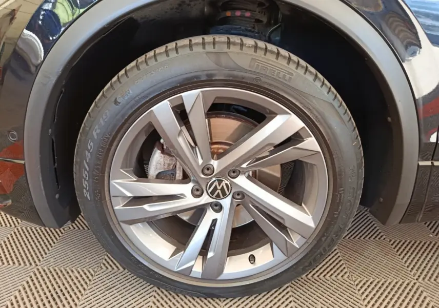 Gros plan sur la roue avant droite du Volkswagen Tiguan noir, jante alliage moderne à plusieurs branches.