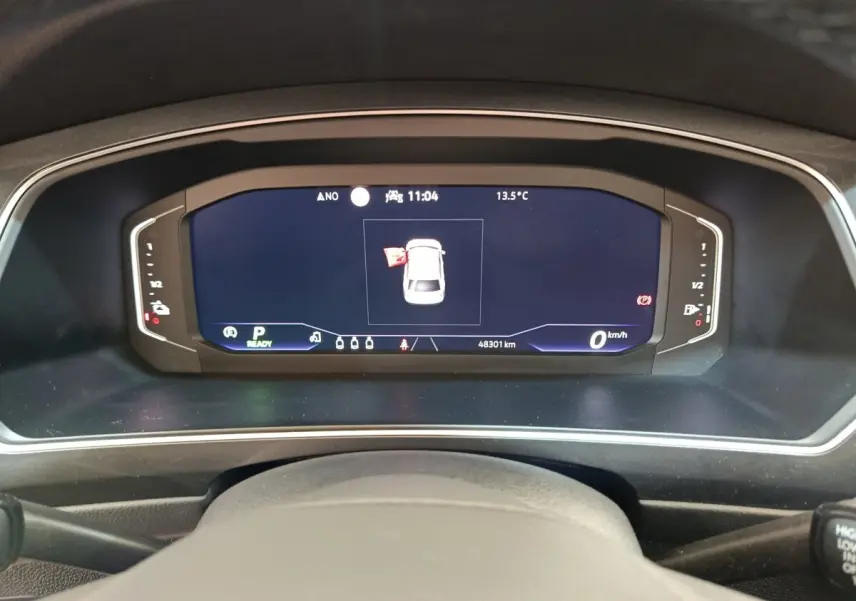 Vue rapprochée du tableau de bord numérique du Volkswagen Tiguan noir, affichant une porte ouverte et 48 301 km au compteur.