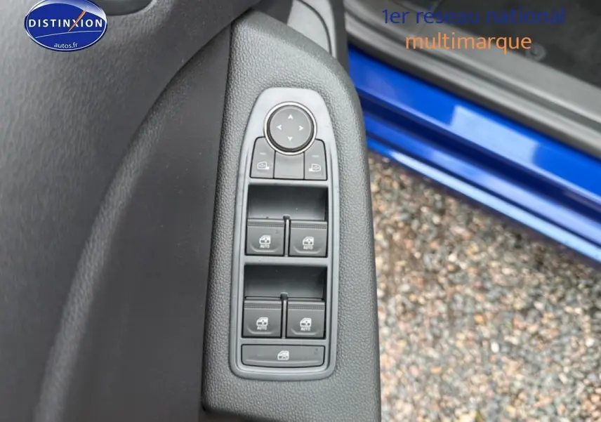 Vue rapprochée des commandes des vitres côté gauche sur porte bleu iron d’une Renault Clio V 1.0 TCe 90 Evolution.