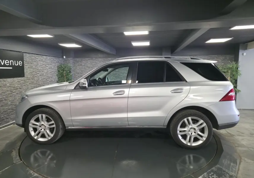 Mercedes Classe M gris métallisé vue de profil côté gauche, vitres teintées et jantes alliage 5 branches doubles.