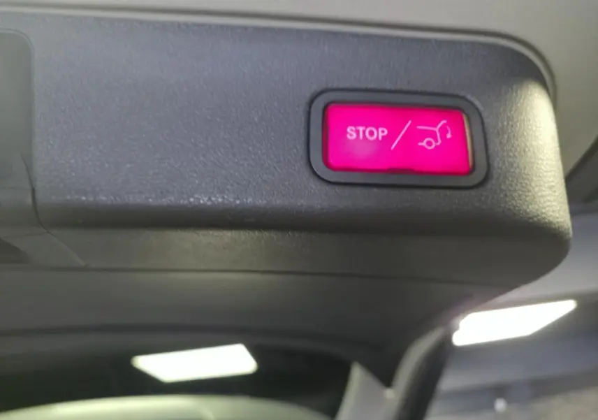 Bouton rouge d'ouverture/fermeture électrique du hayon sur le coffre d'un Mercedes Classe M gris.