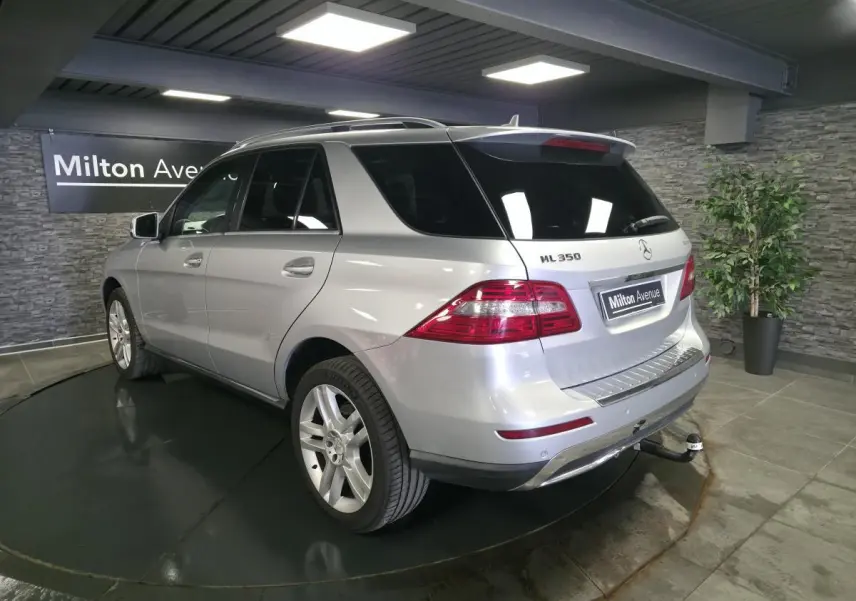 Vue 3/4 arrière droite d'un Mercedes Classe M ML 350 BlueTEC gris métallisé avec attelage et vitres teintées.