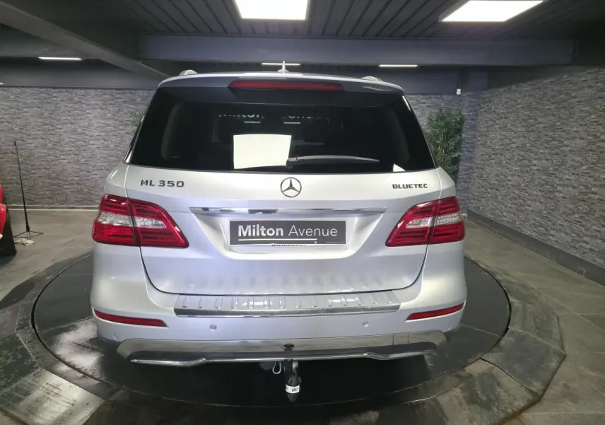 Vue arrière d'un Mercedes Classe M ML 350 gris métallisé avec attelage démontable et feux LED dans un showroom.