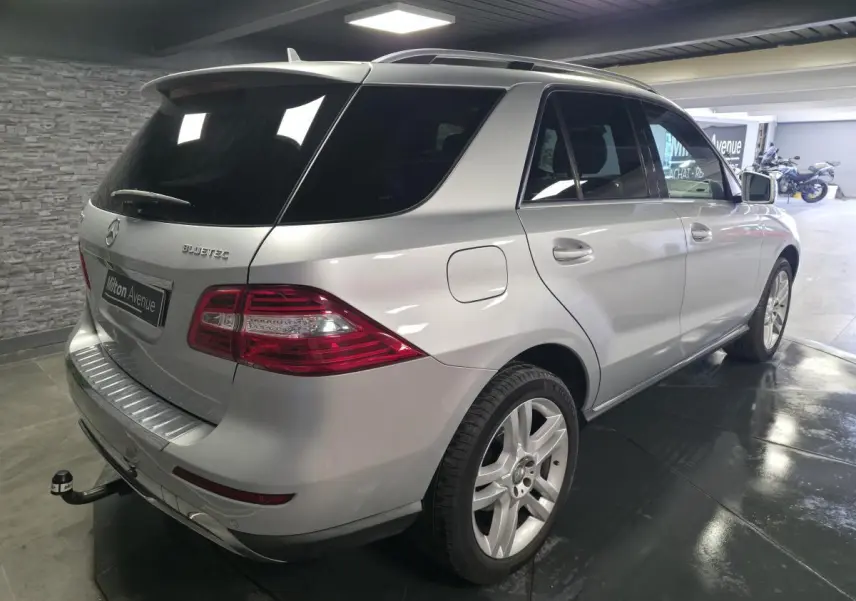 Vue 3/4 arrière droit d'un Mercedes Classe M gris métallisé avec attelage démontable et vitres arrière teintées.
