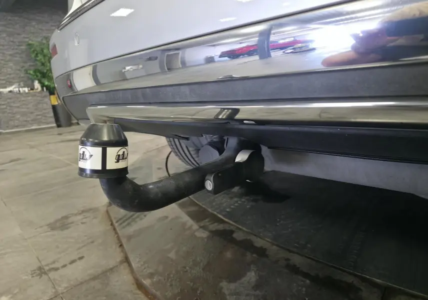 Gros plan sur l'attelage démontable noir sous le pare-chocs arrière gris métallisé d'un Mercedes Classe M 2014.