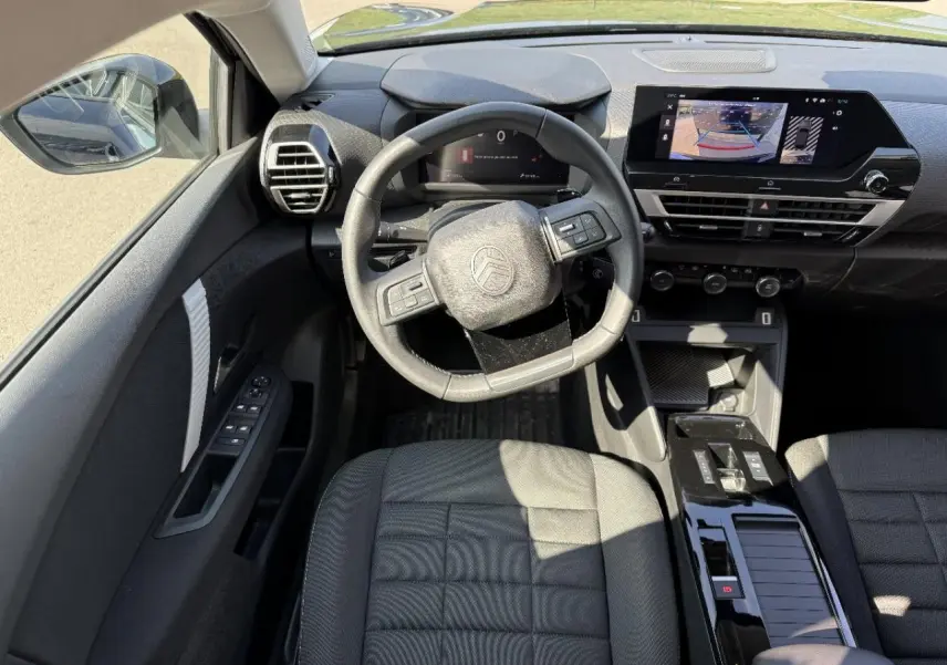 Vue intérieure de face du poste de conduite de la Citroën C4 2025, avec volant multifonction et écran tactile central.