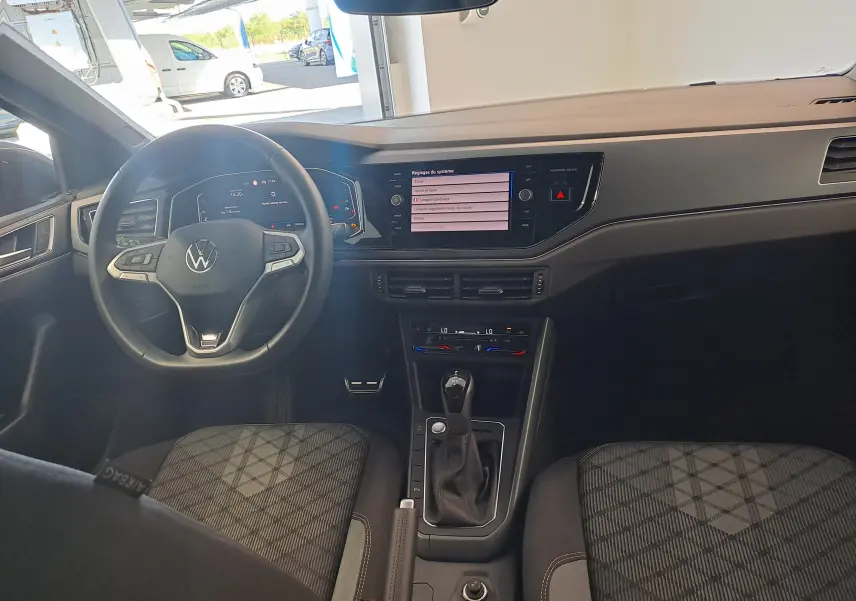 Vue intérieure avant du Volkswagen Taigo 2025, tableau de bord moderne avec écran tactile et volant multifonction noir.