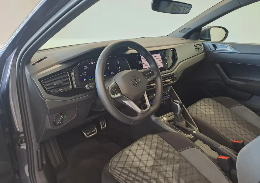 Vue intérieure côté conducteur du Volkswagen Taigo 1.0 TSI 116 DSG7 R-Line Edition avec sièges tissu gris à motif losange.