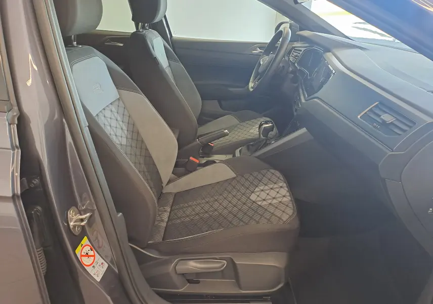 Vue intérieure côté conducteur du Volkswagen Taigo gris cendre 2025, sièges tissu à motif géométrique et tableau de bord moderne.